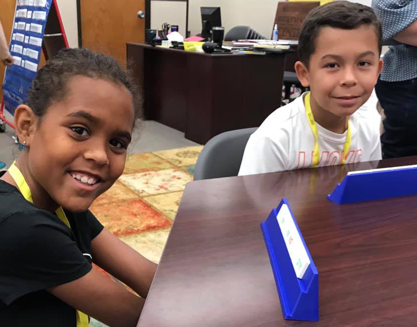 two students sitting at a table playing a reading game