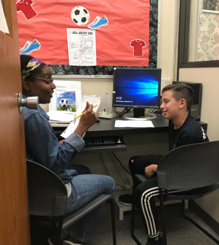 A tutor teaching a student in front of a computer