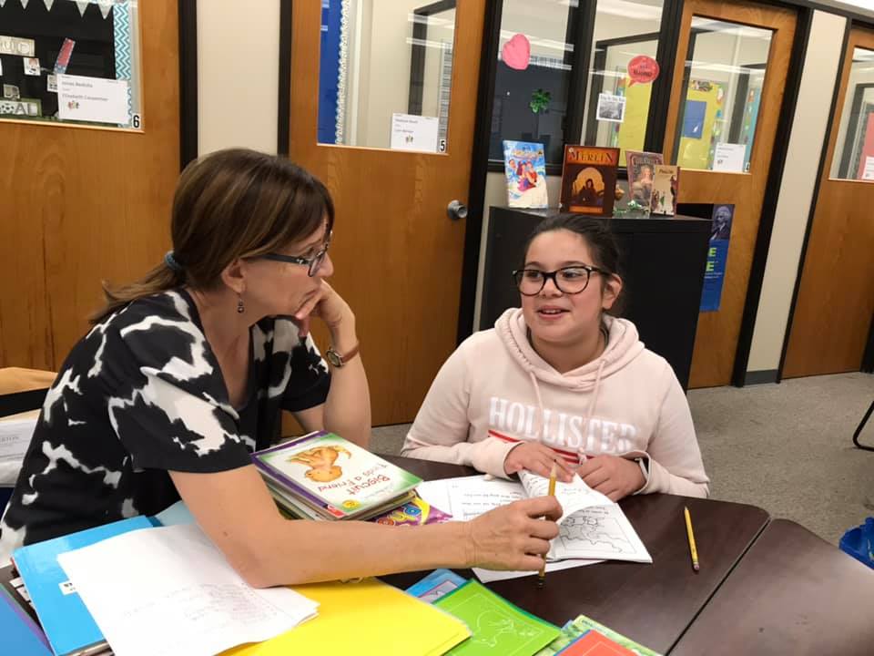 A teacher and a girl discussing a book